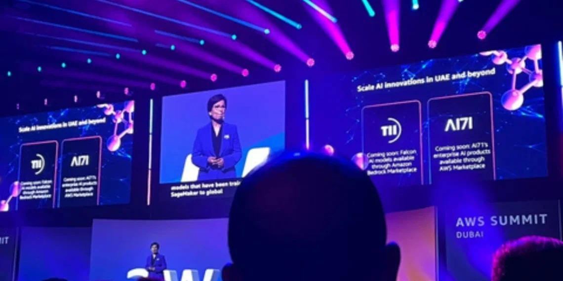 متحدثة تستعرض التعاون بين الإمارات وأمازون خلال قمة AWS في دبي، مع عرض مرئي لنماذج فالكون ومنتجات AI71 على الشاشات الرئيسية