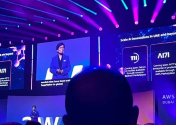 متحدثة تستعرض التعاون بين الإمارات وأمازون خلال قمة AWS في دبي، مع عرض مرئي لنماذج فالكون ومنتجات AI71 على الشاشات الرئيسية