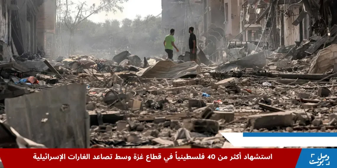 مشهد دمار واسع في قطاع غزة بعد قصف إسرائيلي، يظهر ركام مبانٍ مدمرة واثنين من المدنيين يمشون وسط الأنقاض، يعكس مأساة استشهاد أكثر من 40 فلسطينياً جراء القصف.