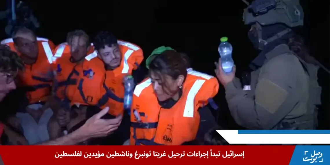 جندي إسرائيلي يقدم الماء لركاب يخت "مادلين" المتجه إلى غزة، بعد اعتراضه خلال محاولة كسر الحصار البحري، ضمن رحلة ضمت غريتا ثونبرغ. (رويترز)