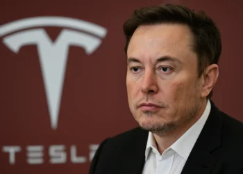 صورة تعبر عن إيلون ماسك بجانب شعار تسلا وسط أجواء توتر حول تراجع أسهم الشركة بعد الإعلان عن الحزب الأمريكي