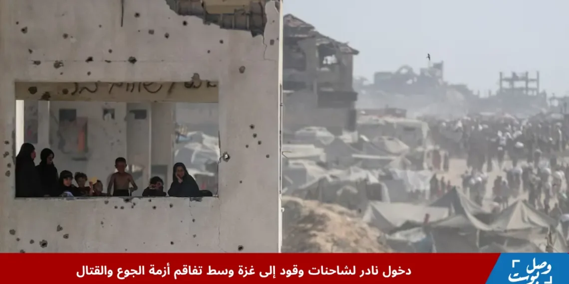 أطفال ونساء يراقبون من نافذة مبنى مدمر في غزة بينما يظهر في الخلف مشهد لمخيمات النزوح، وسط تفاقم الأزمة الإنسانية بالتزامن مع دخول شاحنات وقود غزة النادرة لتخفيف المعاناة المتصاعدة